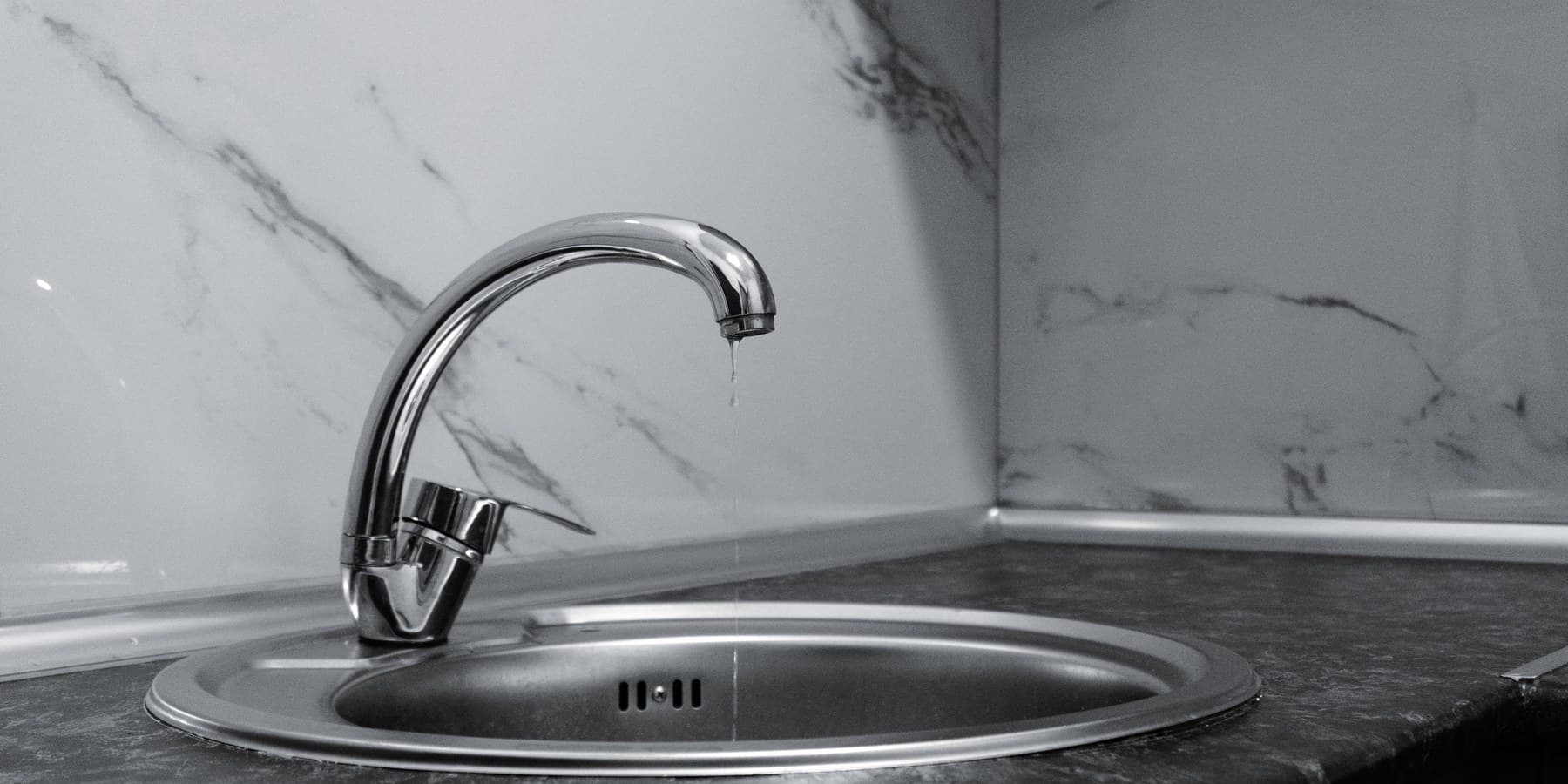A chrome faucet on a finished marble bathroom install