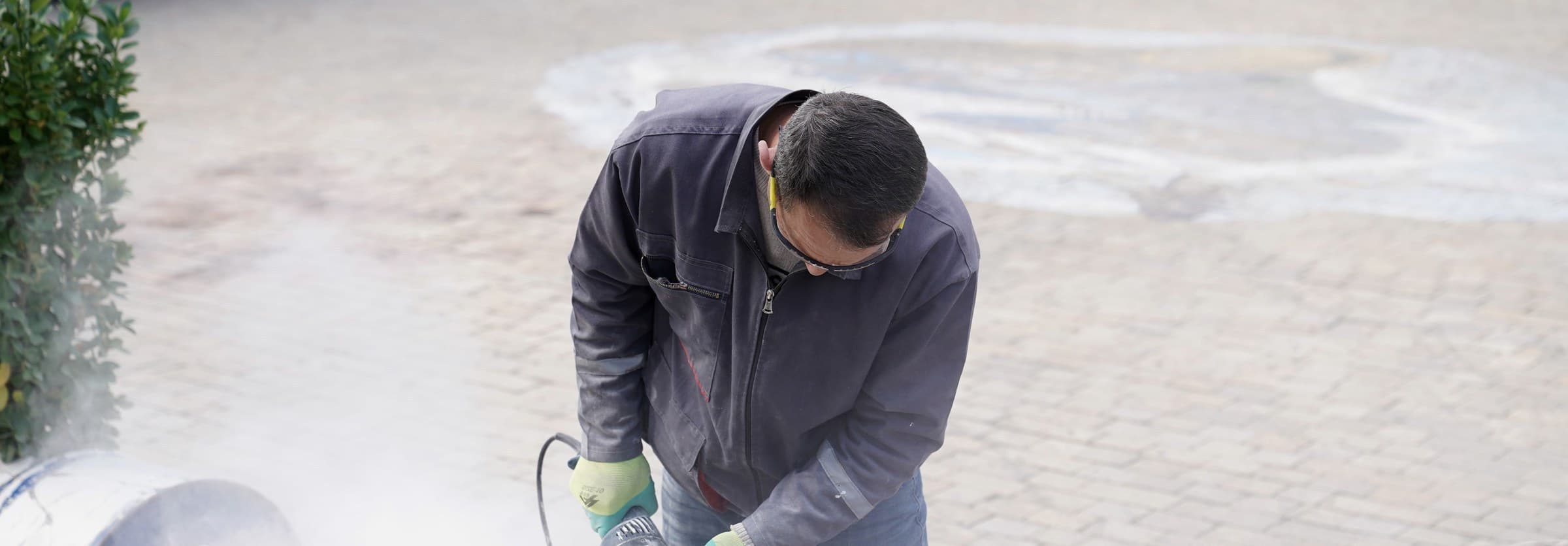A worker cutting stone tile with a power saw on an outdoor flooring job