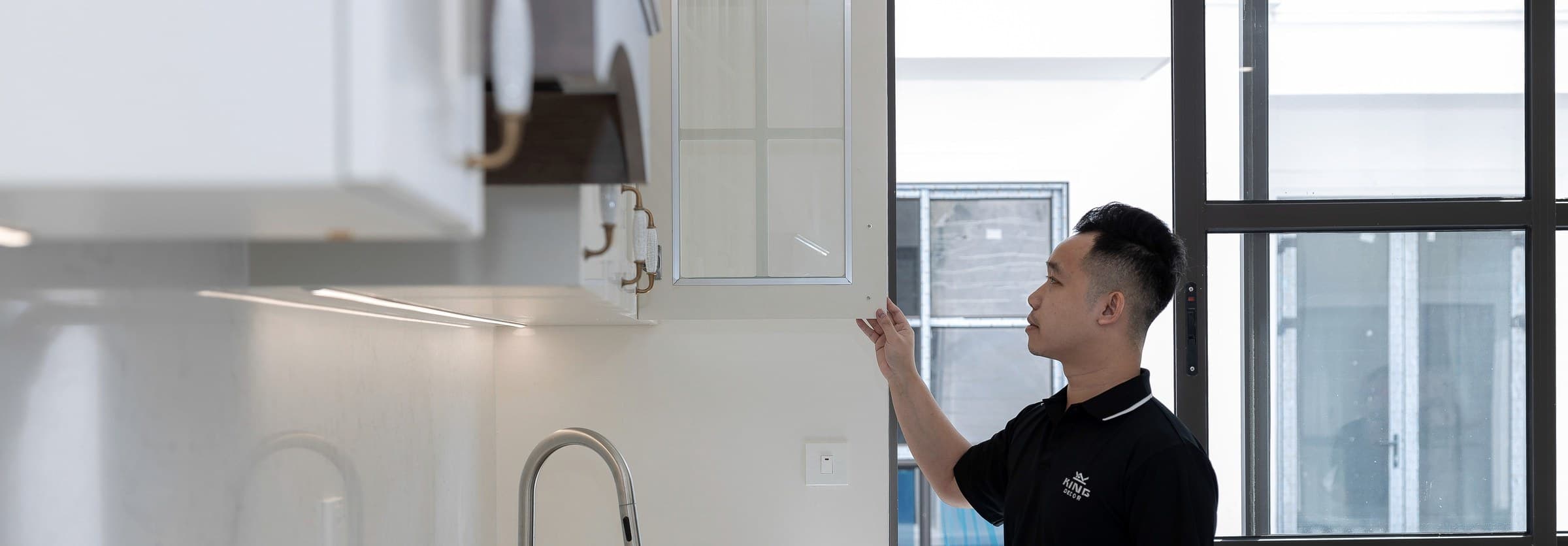 A contractor checking the fit of new cabinet doors in a finished kitchen remodel